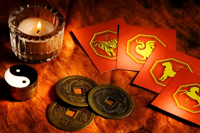 Chinese coins and a candle on a table, symbolizing a step-by-step I Ching guide and the concept of Yin-Yang balance in I Ching readings.