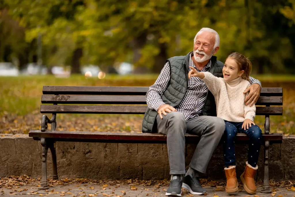 Grandfather and granddaughter on a park bench in autumn, symbolizing connection and trust in I Ching Hexagram 61's practical wisdom.